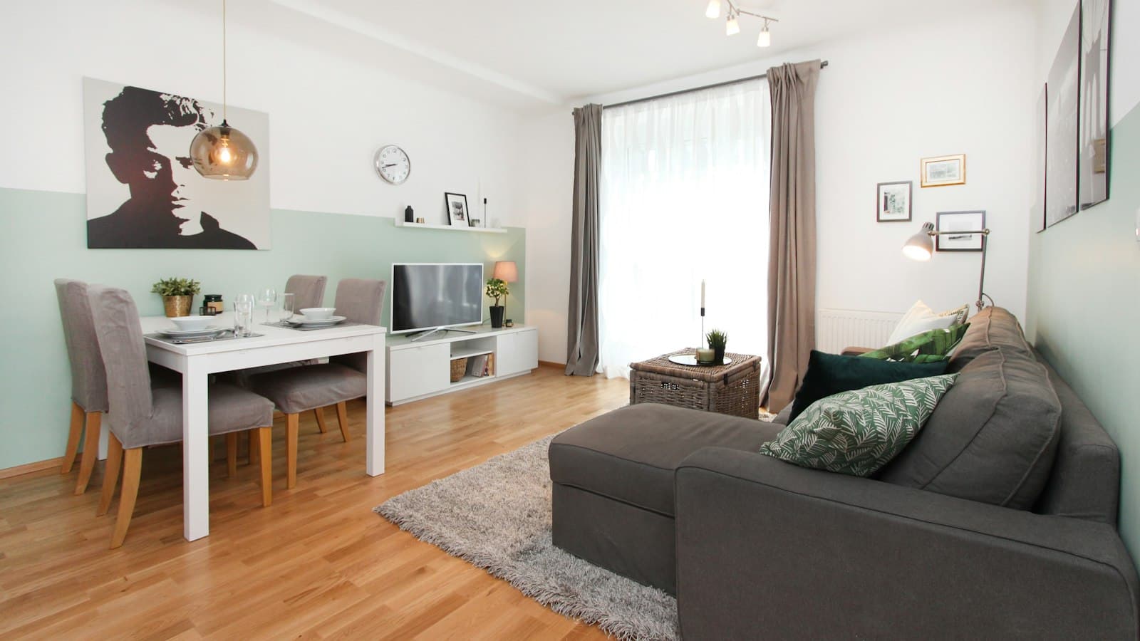 Helles Wohnzimmer mit Sofa, Esstisch und großem Fenster in einer Wohnung
