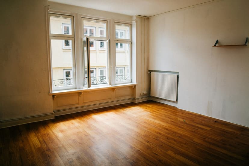 Leergeräumtes Zimmer mit Parkettboden, Altbaufenster und Heizkörper