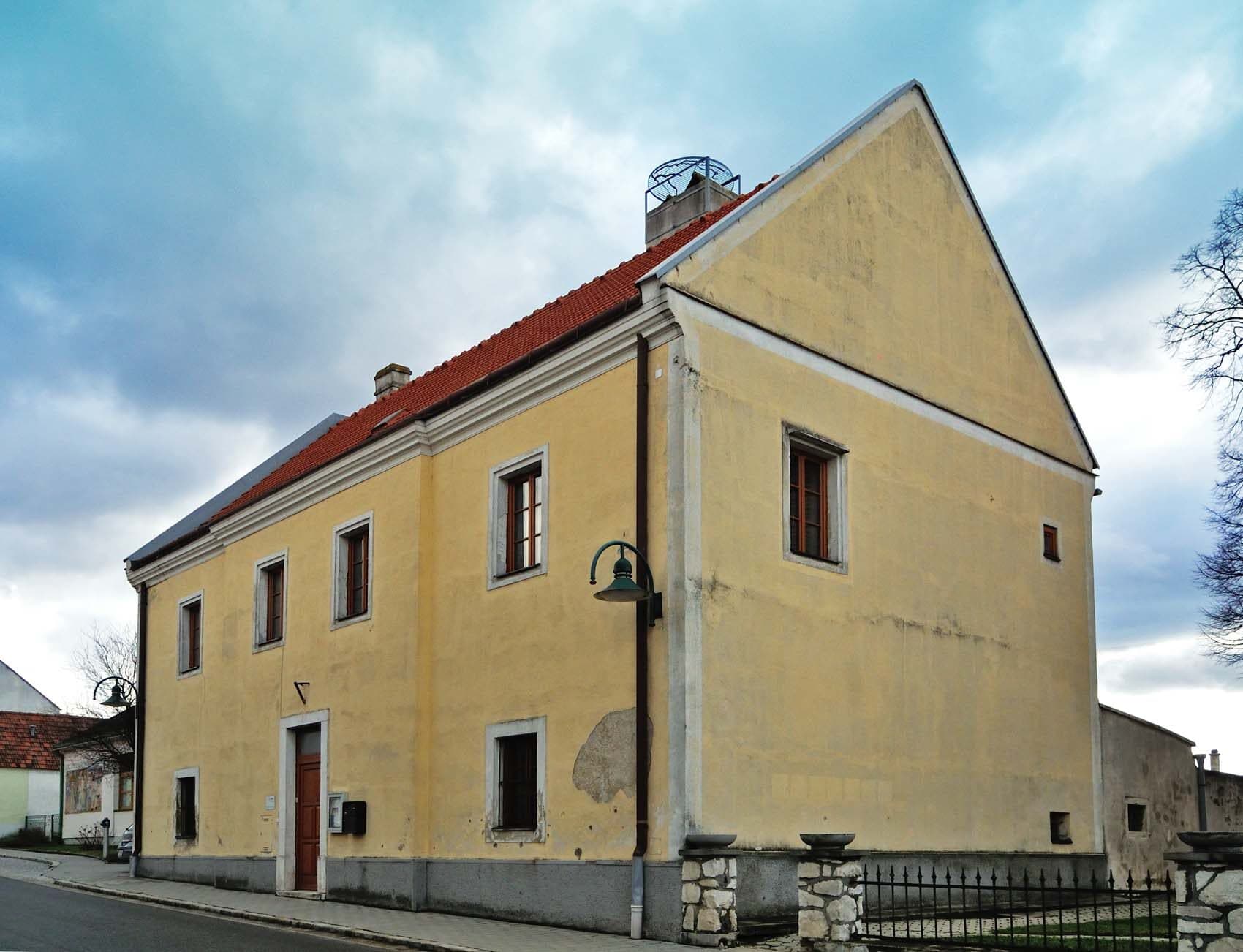 Historischer Pfarrhof (gelbes Gebaeude) in Hof am Leithaberge mit blauem Himmel