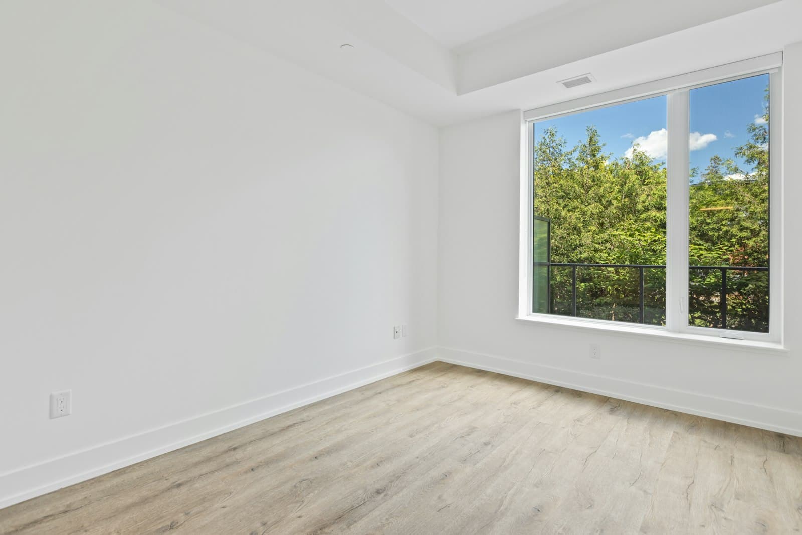 Leerer heller Wohnraum mit großem Fenster und Parkettboden