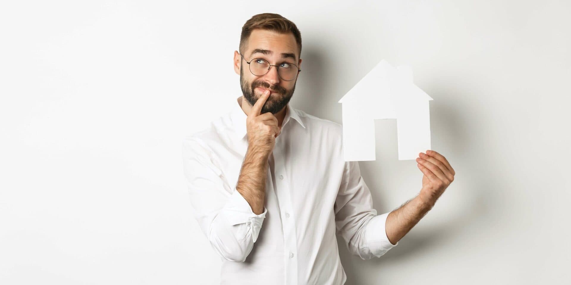 Nachdenklicher Mann mit einem Modellhaus in der Hand