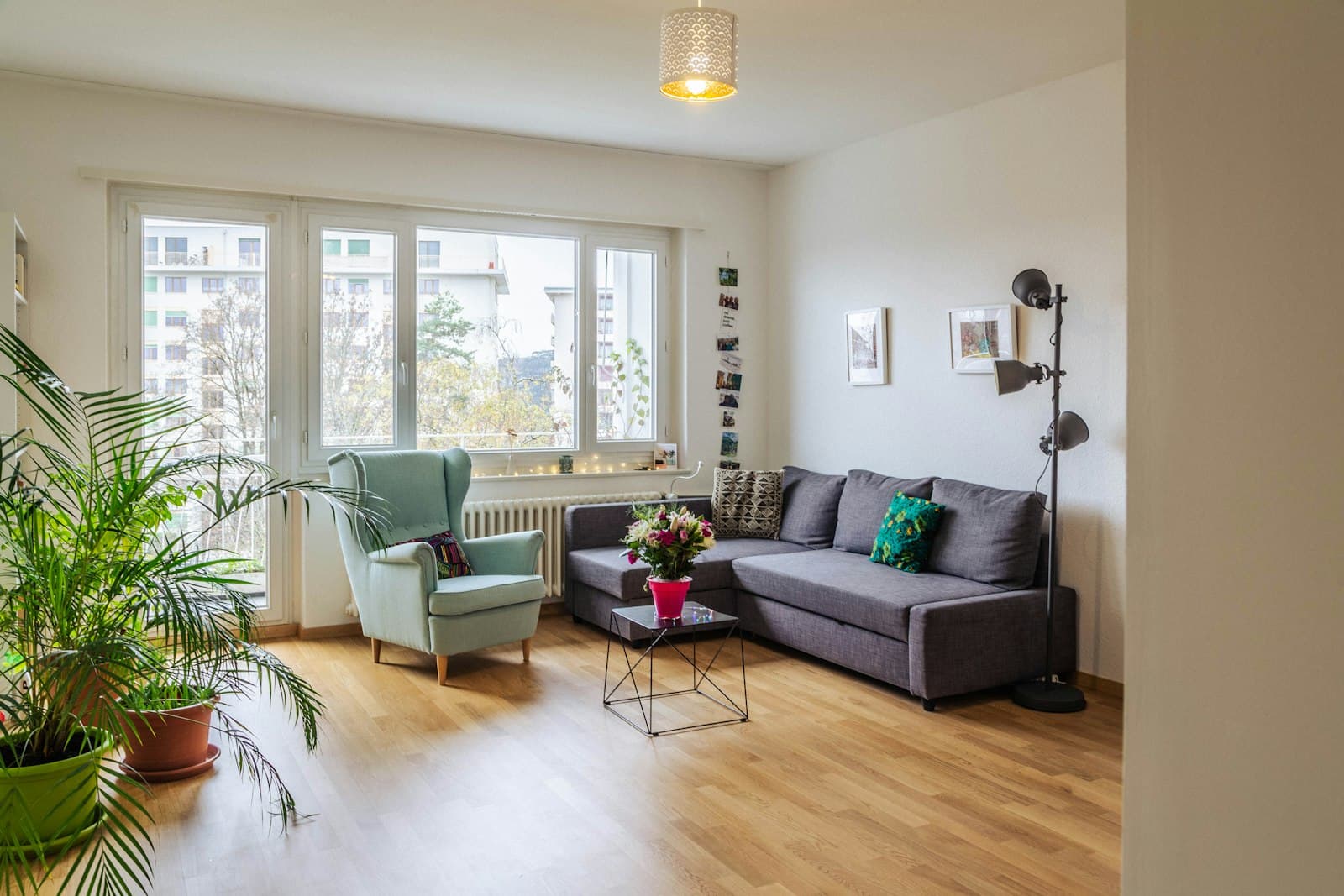 Helles Wohnzimmer mit Sofa, Sessel und großem Fenster