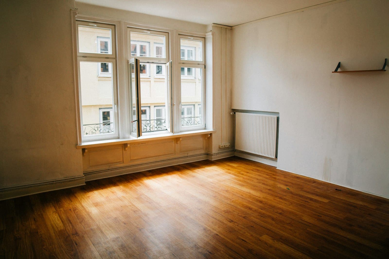 Leergeräumtes Zimmer mit Parkettboden, Altbaufenster und Heizkörper